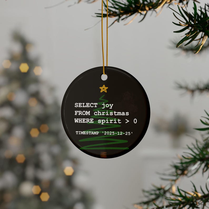 a Christmas ornament hanging from a tree branch. The ornament has a black background with white text and a green tree design.