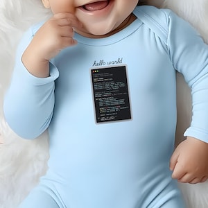 A smiling baby wearing a light blue onesie with a programming code printed on it.