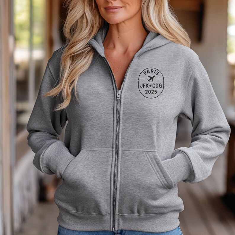 A woman wearing a grey hooded sweatshirt with a logo on the front.