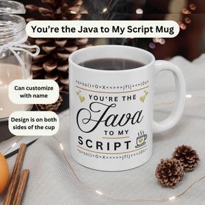 May include: A white ceramic mug featuring the black text "YOU'RE THE Java TO MY SCRIPT" with gold heart accents and a small coffee cup icon. The design includes lines of code-like characters at the top and bottom of the printed graphic.