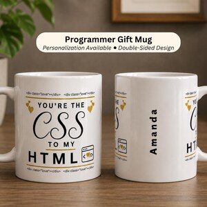 May include: Two white ceramic mugs featuring black and gold text that reads "YOU'RE THE CSS TO MY HTML" with a small browser icon containing a heart. The side of one mug is personalized with the name "Amanda" in black vertical text.