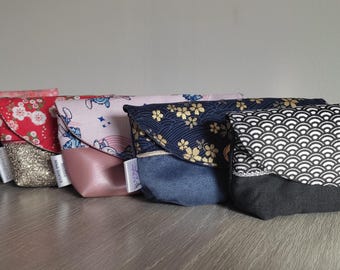 May include: A set of six small fabric pouches with different patterns. The pouches are made of cotton and have a flap closure. The patterns include a pink floral design, a red and gold design, a pink and white design, a blue and gold design, a black and white design, and a black and white geometric design.