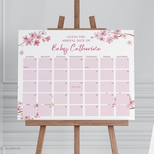May include: A rectangular sign featuring a calendar grid for April and May with the text GUESS THE ARRIVAL DATE OF Baby Catherine. The design includes pink cherry blossom branches in the corners and light pink squares for each day.