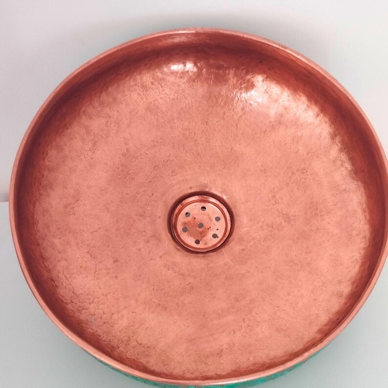 May include: A copper bathroom sink with a hammered finish and a round drain.