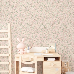Peut inclure: Un ensemble bureau et chaise en bois clair avec une figurine de lapin rose, des crayons et des livres. Le fond est un papier peint floral rose et vert. Une échelle en bois et des blocs de jouets sont également visibles.