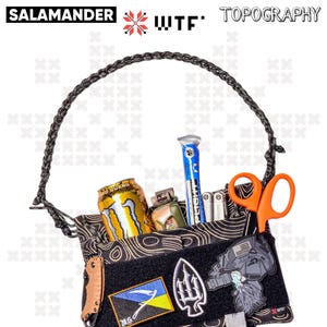 Puede incluir: Una bolsa táctica negra con una correa trenzada, que presenta un patrón topográfico. La bolsa está llena de varios artículos, incluyendo una lata de bebida energética Monster, un encendedor, una multiherramienta, un par de tijeras y un parche azul y amarillo con un símbolo de tridente. La bolsa también tiene un parche con una imagen estilizada de una persona con casco y barba. La bolsa tiene el texto "WTF" y "TOPOGRAPHY" impreso en ella.