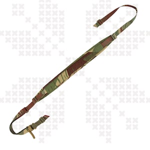 Puede incluir: Una correa para rifle con patrón de camuflaje en tonos marrones y verdes. Cuenta con correas ajustables y herrajes metálicos. Se puede leer el texto "RHODESIAN BRUSHSTROKE". Diseñada para armas de fuego.