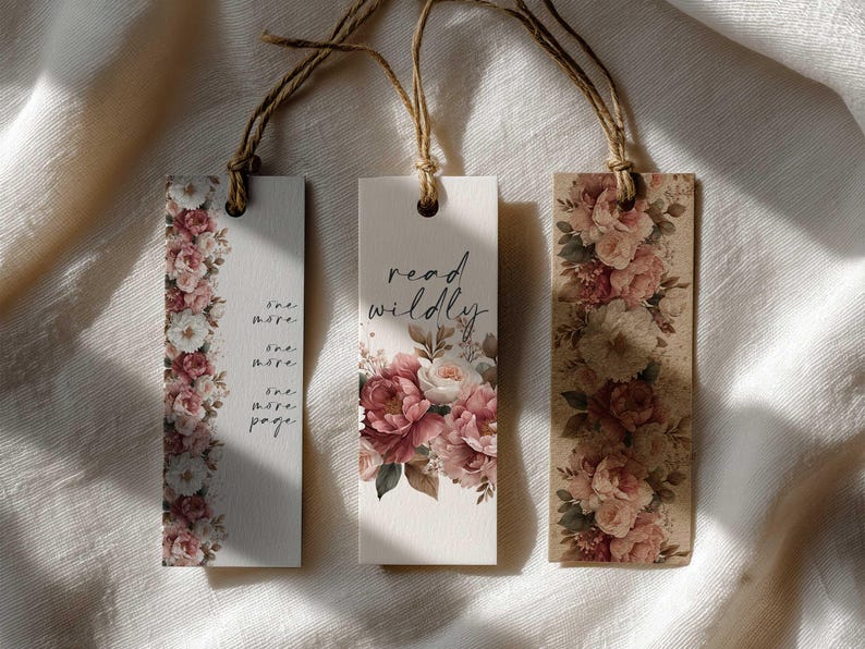 May include: Three floral bookmarks with twine strings. One bookmark has the text "one more page" and a floral border. Another bookmark says "read wildly" with a floral design. The third bookmark has a floral design.