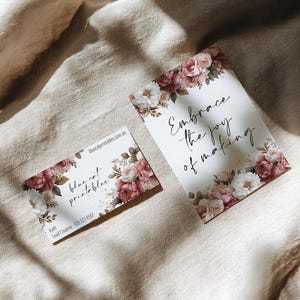May include: Two cards with floral designs. One card reads "Embrace the joy of making" in script. The other card has the text "blue cat printables" and contact information. Both cards feature pink and white flowers.