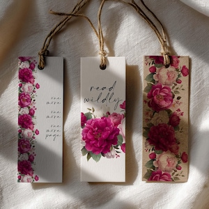 May include: Three floral bookmarks with twine strings. One bookmark has a vertical floral border with the text "one more, one more, one more, page." The second bookmark says "read wildly" with a floral design. The third bookmark has a floral design.