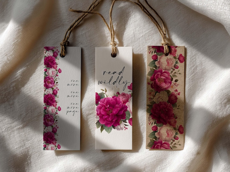 May include: Three floral bookmarks with twine strings. One bookmark has a vertical floral border with the text "one more, one more, one more, page." The second bookmark says "read wildly" with a floral design. The third bookmark has a floral design.