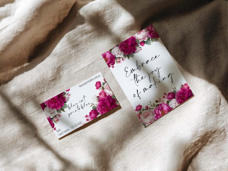 May include: Two white cards with floral designs and text. One card reads "Embrace the joy of making" with a border of pink and white flowers. The other card has the text "blue cat printables" and contact information, also with floral accents.