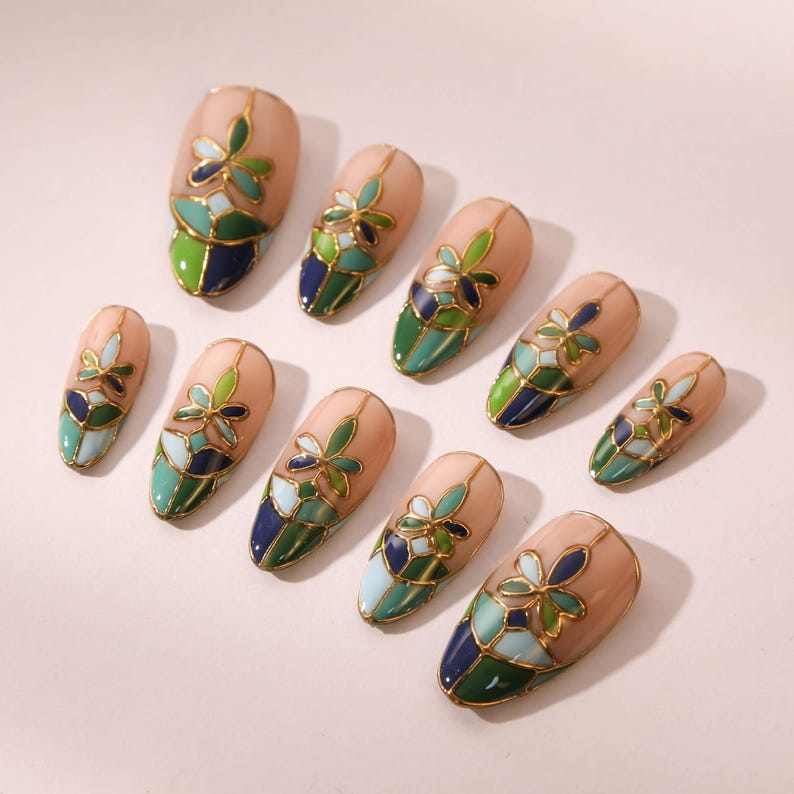 Puede incluir: Conjunto de diez u&ntilde;as postizas con un dise&ntilde;o de vitral con detalles en verde, azul y dorado. Cada u&ntilde;a tiene un patr&oacute;n floral.