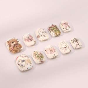 May include: Set of ten white false nails with different cute cartoon animal and floral designs.