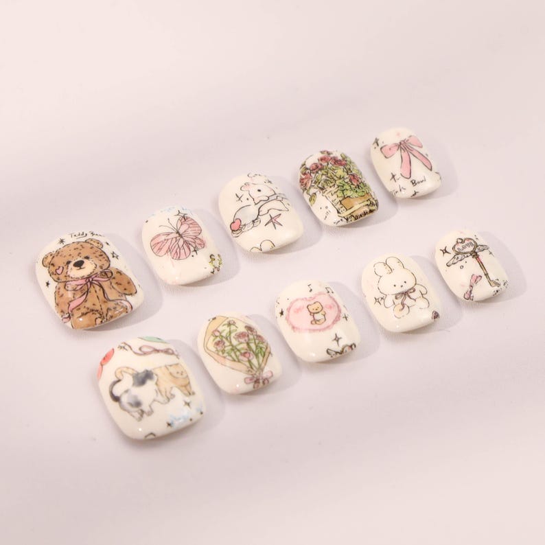 May include: Set of ten white false nails with different cute cartoon animal and floral designs.