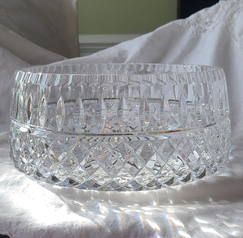 Puede incluir: Un cuenco de cristal tallado transparente, de forma ancha y redonda. El cuenco presenta un patr&oacute;n de diamantes en la mitad inferior y cortes verticales en el borde superior. El cristal refleja la luz, creando un efecto brillante. Este cuenco decorativo es adecuado para servir o exhibir.