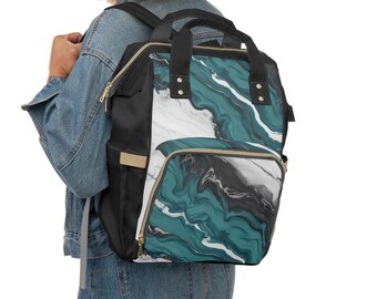 May include: A black and teal backpack with a marble design. The backpack has a top handle, two side pockets, and a front pocket. The bag has gold zippers and black straps. The backpack is being worn by a person.