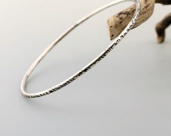 May include: A silver bangle bracelet with a textured surface.