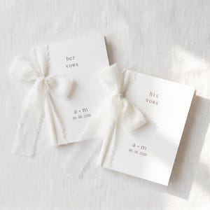 Può includere: Due libretti di promesse bianchi, uno con "her vows" e l'altro con "his vows", legati con nastri bianchi. La data "06.06.2026" è stampata su ogni libretto con un carattere minimalista.