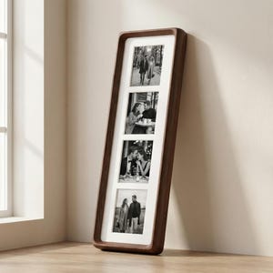 Puede incluir: Un marco de fotos rectangular marrón oscuro con cuatro aberturas, cada una con una fotografía en blanco y negro. El marco tiene un borde redondeado y un borde blanco alrededor de cada foto. El marco está apoyado contra una pared.