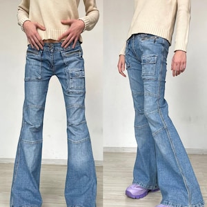 May include: Light blue denim jeans with cargo pockets and a flared leg. The jeans have zip details and are paired with a cream-coloured sweater and purple trainers. The sweater has the letters "DKNY" on it.