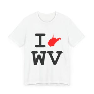 Könnte beinhalten: Weißes T-Shirt mit einer schwarzen Grafik, auf der "I love WV" steht, mit einer roten Umrandung des Bundesstaates West Virginia in Form eines Herzens.