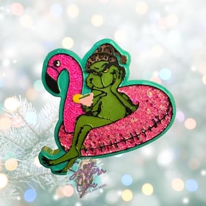 May include: A green cartoon character wearing a leopard print hat, relaxing on a pink flamingo pool float. The float has pink glitter. The character is holding a drink. The image has the text "Southern Chic" and "More".