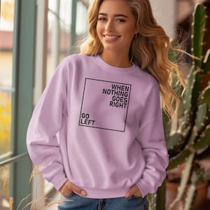 May include: A light purple sweatshirt with a black square graphic that says "WHEN NOTHING GOES RIGHT GO LEFT".