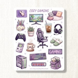 Può includere: Un foglio di adesivi intitolato COZY GAMING con illustrazioni di un monitor per computer, sedia da gaming, tastiera, controller, console portatile, case per PC, portapenne a forma di gatto, pianta grassa, cuffie, pantofole, bevanda e uno zaino.