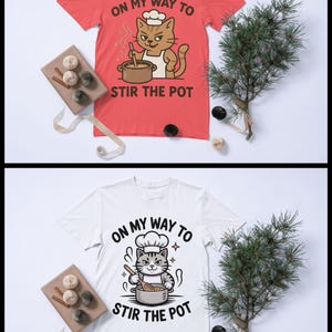 May include: Red t-shirt with a cat chef graphic and the text "ON MY WAY TO STIR THE POT." The cat is stirring a pot. A white t-shirt with the same graphic is also shown. The shirts are displayed with decorative elements.