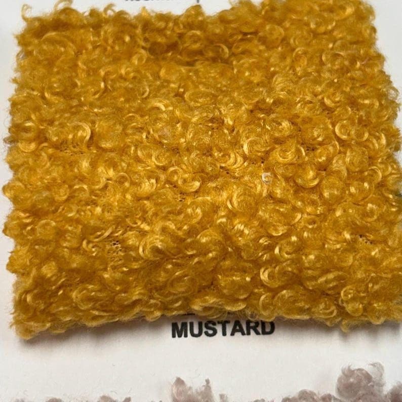 A square swatch of mustard yellow curly teddy fleece fabric with the word MUSTARD printed below.