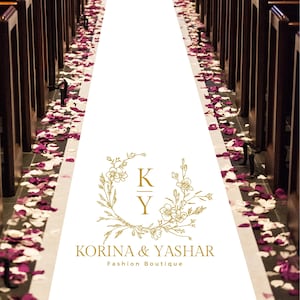 May include: A wedding aisle with a white runner, lined with dark wooden pews. The aisle is scattered with red and white rose petals. A gold floral logo with the text "KORINA & YASHAR Fashion Boutique" is in the foreground.