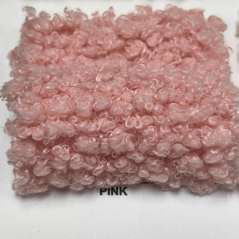 A square swatch of pink curly teddy fleece fabric with the word PINK printed below.