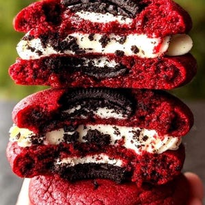 Może przedstawiać: Stos ciasteczek typu red velvet z kremowym białym nadzieniem i ciemnym czekoladowym ciasteczkiem pośrodku. Ciasteczka są przecięte, aby odsłonić warstwy kremu i ciasta.