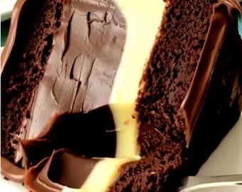 May include: A slice of chocolate cake with a creamy white filling and a rich chocolate ganache topping. The cake has a dark brown, moist appearance, with visible layers and textures. A fork is visible at the bottom, suggesting it's ready to be enjoyed.