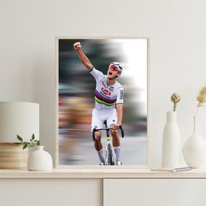 Puede incluir: Un ciclista con un maillot blanco con rayas arcoíris y un logotipo de patrocinador rojo y blanco levanta el brazo en señal de victoria. Lleva un casco y gafas de sol y monta en bicicleta con un cuadro negro y neumáticos blancos.