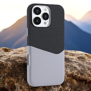 May include: A black and gray phone case with a textured fabric design and a gray leather-like flap. The case has a cutout for the phone's camera lenses.