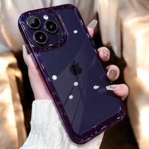 Könnte beinhalten: Eine transparente Handyhülle mit einem violetten Farbton und einem erhöhten Rand um die Kameralinsen. Die Hülle hat einen dezenten Glitzereffekt.