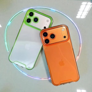 Peut inclure: Deux coques de téléphone transparentes avec des cadres colorés. L'une a un cadre vert, l'autre un cadre orange. Les deux coques ont un dos transparent avec le logo Apple visible. Les coques sont conçues pour un smartphone à trois objectifs.