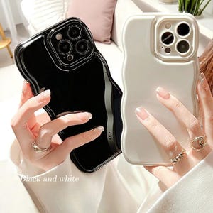 Op de afbeelding: Twee telefoonhoesjes, één zwart en één wit, met een golvend randontwerp. De hoesjes hebben een glanzende afwerking. De tekst "Black and white" is zichtbaar onderaan de afbeelding.