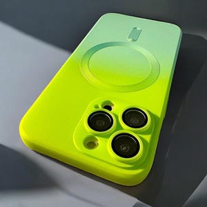 Könnte beinhalten: Eine Handyhülle mit Farbverlauf in Neongrün und Hellgrün. Die Hülle hat ein kreisförmiges Design auf der Rückseite und Aussparungen für die Kameralinsen des Telefons. Die Hülle soll das Telefon vor Kratzern und Beschädigungen schützen.