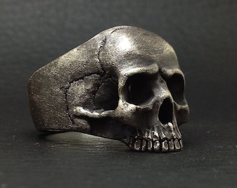 Puede incluir: Un anillo de calavera de plata con un diseño detallado. El anillo está hecho de metal y tiene un diseño de calavera realista.