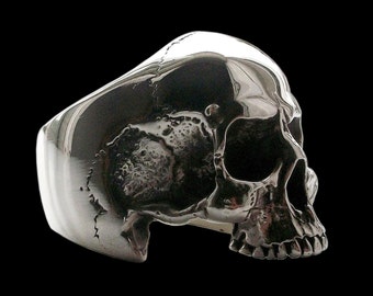 Puede incluir: Un anillo de calavera de plata con un diseño detallado. El anillo está hecho de metal pulido y tiene un diseño de calavera realista.