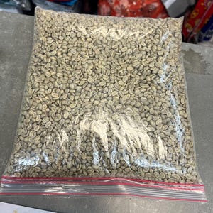 Peut inclure: Un sac en plastique transparent rempli de grains de café verts. Le sac a une fermeture éclair rouge.