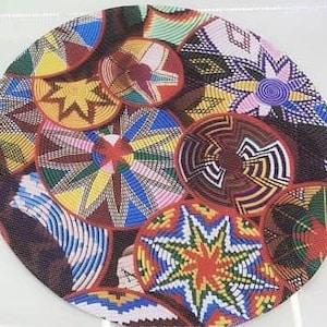 May include: A round placemat featuring a collage of colorful, woven basket designs. The designs include various geometric patterns in shades of red, yellow, blue, green, and brown. The placemat is approximately 12 inches in diameter.