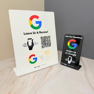 May include: Two white and black Google review signs. The larger sign says "Leave Us A Review!" with a QR code and a graphic of a phone. The smaller sign says "Rate Your Experience" and "review us on Google". Both signs feature the Google logo.