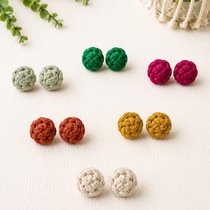 Peut inclure: Six paires de boucles d'oreilles à tige sphériques en cordon tressé de différentes couleurs, dont vert sauge, vert forêt, magenta, orange brûlé, jaune moutarde et crème. Chaque boucle présente un motif noué texturé de forme ronde.
