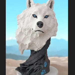 May include: White wolf bust sculpture with blue eyes. The bust is made of a white material and has a black base with blue paw prints.
