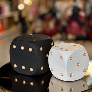 May include: Two large dice shaped decorative objects. One is black with gold dots and the other is white with gold dots.