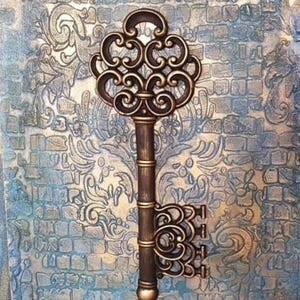 May include: A large, ornate, gold-toned key with intricate details and a decorative handle. The key is set against a textured, blue and gold background.
